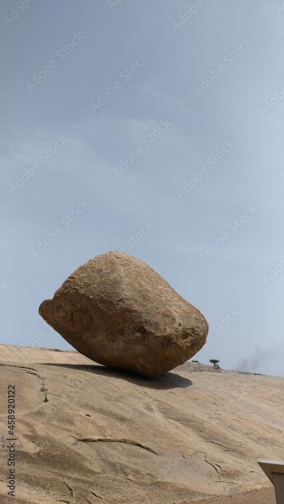 huge rock balancing on a rock cut hill