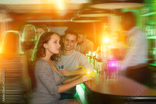 Cheerful young man flirting with women bar counter and drinking cocktails at nightclub
