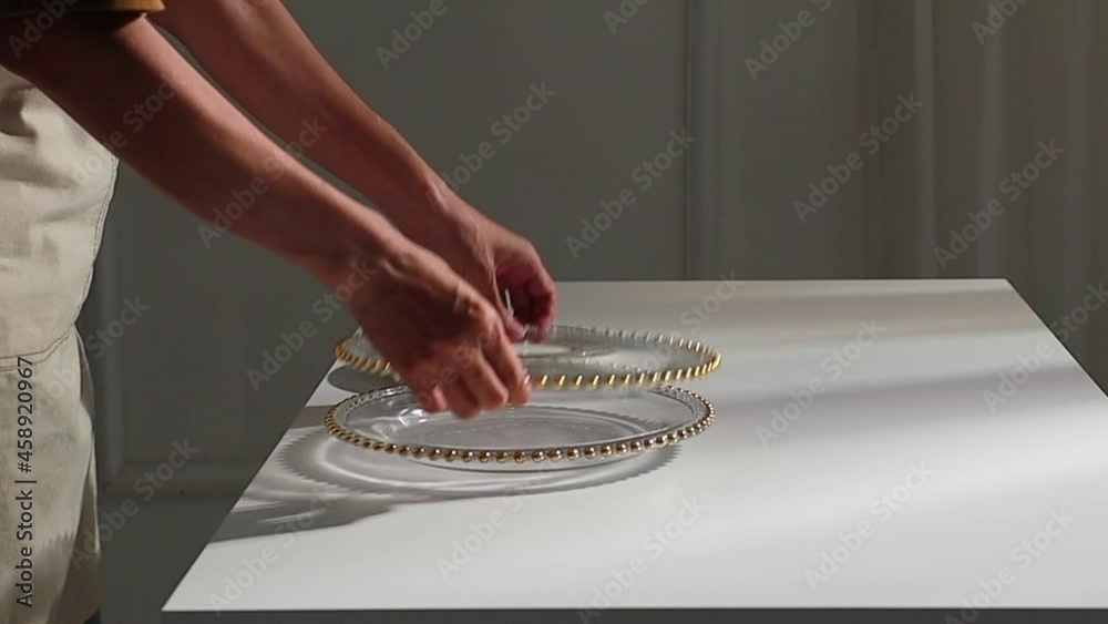 Woman's hand arrange with Decoration wedding ta ble setup with golden cutlery, olive branch, porcelain plate, glass concept.	
