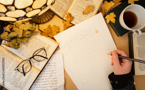 Student studies Shakespeare sonnets surrounded by books and papers. Dark academia aesthetic 