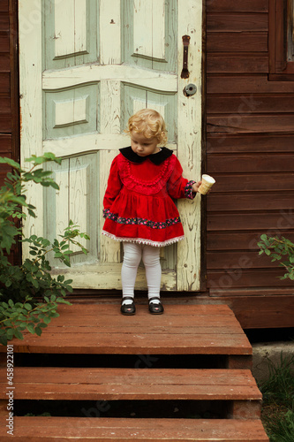 ittle girl with ice cream on the background of the door of the house