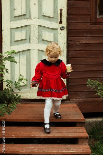 ittle girl with ice cream on the background of the door of the house
