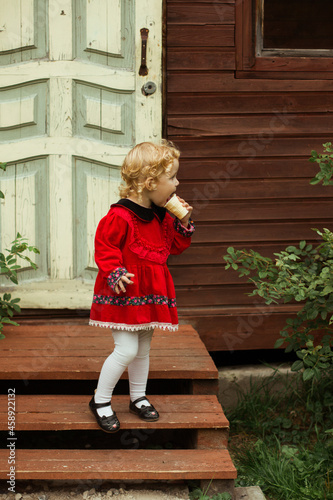 ittle girl with ice cream on the background of the door of the house