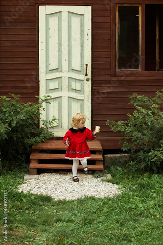 ittle girl with ice cream on the background of the door of the house