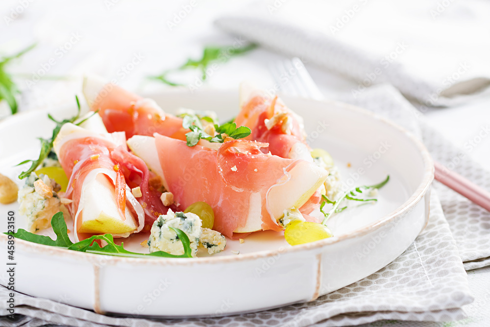 Appetizer with pear, blue cheese and prosciutto ham for holidays on a white plate. Appetizer with pear, blue cheese and prosciutto ham for holidays on a white plate.