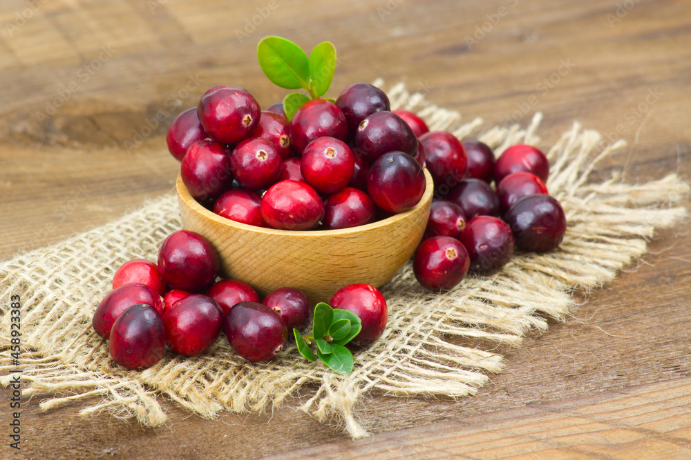 Cranberries in a bowl on wooden background. Cranberries in a bowl on wooden background.