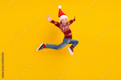 Full size photo of amazed excited small girl jump up raise hands season sale isolated on yellow color background