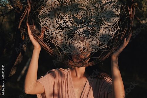 Young woman standing and carrying big lace dream catcher. Boho style girl in the long greek dress holding dream catcher. Boho model.