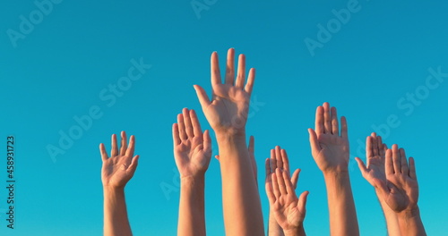Raised hands against blue sky