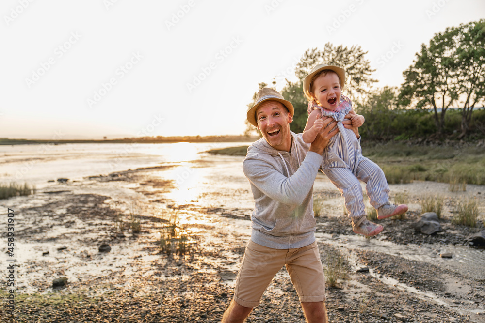 Father have fun with baby on the beach at the sunset