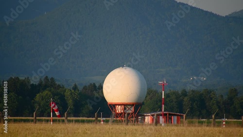 Establishment shot of antenna radar dome at Ljubljana Airport, Slovenia. Beautiful summer sunset. Green forest and mountains in the distance. Static shot