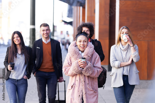 Group of people walking on a street with confidence. Businessmen and businesswomen traveling together..