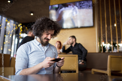 Man at a modern cafe looking at phone.