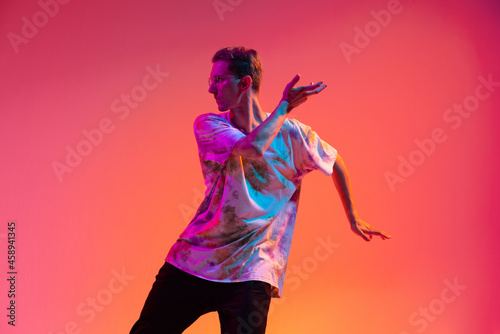 Canvas Print Cropped portrait of attractive young man practising hip-hop dance isolated over