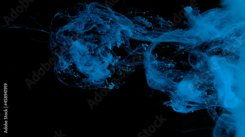 Blue watercolor paints in water on a black background. Awesome abstract background. Beautiful wallpaper for your desktop. Blue cloud of ink on a black background.