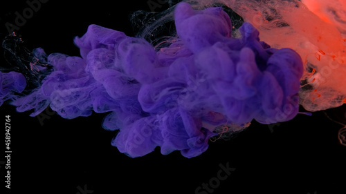 Beautiful wallpaper for your desktop. Colored cloud of ink on a black background. Drops of pink and purple ink in water. Pink and purple watercolor paints in water on a black background.