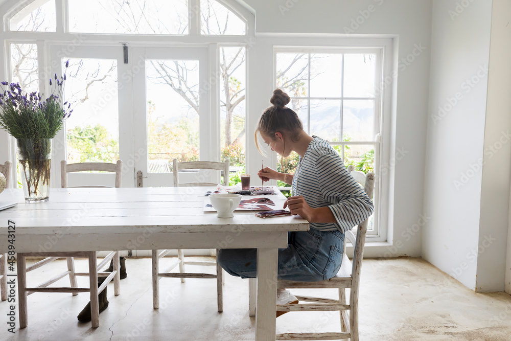 Teenage girl painting with watercolors in a light filled room Teenage girl painting with watercolors in a light filled room