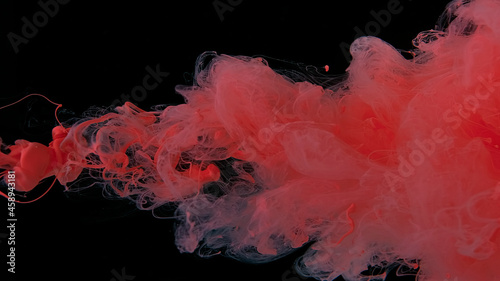Beautiful wallpaper for your desktop. Pink cloud of ink on a black background. Drops of pink ink in water. Pink watercolor paints in water on a black background.
