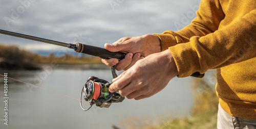 Male hands of a fisherman are holding a spinning closeup. Concept of fishing in the autumn forest