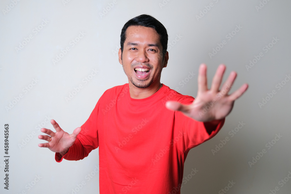 Naklejka premium Adult Asian man showing happy face expression while running forward to reach something
