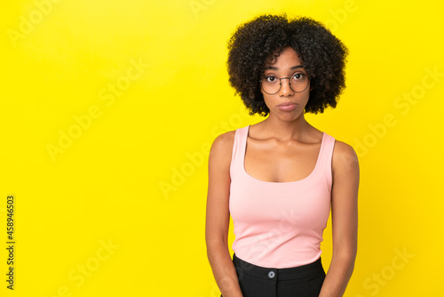Young African American woman isolated on yellow background with sad expression