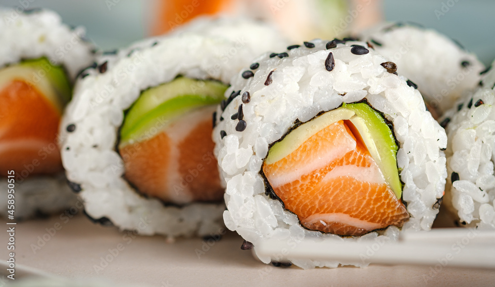 A set of fresh sushi rolls with salmon, avocado and black sesame seeds close up. California roll, selective focus A set of fresh sushi rolls with salmon, avocado and black sesame seeds close up. California roll, selective focus