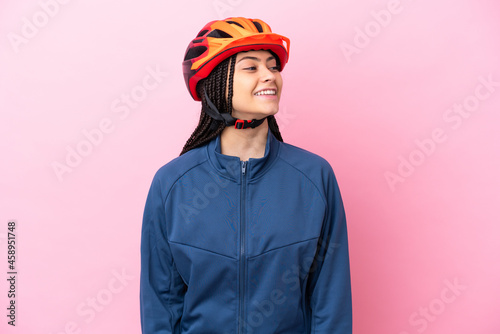 Teenager cyclist girl isolated on pink background looking side © luismolinero