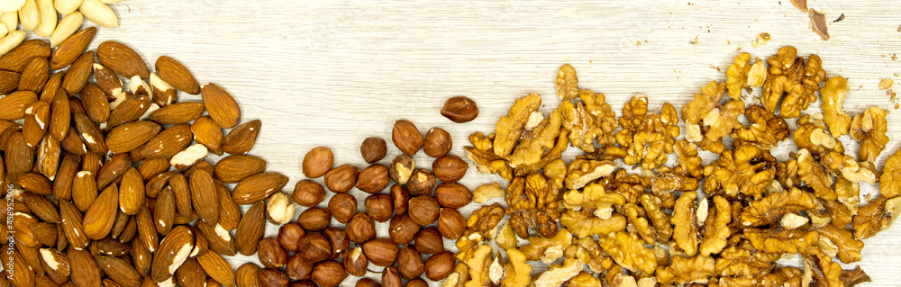 banner assortment of nuts hazelnuts, walnuts, almonds on wood table banner assortment of nuts hazelnuts, walnuts, almonds on wood table