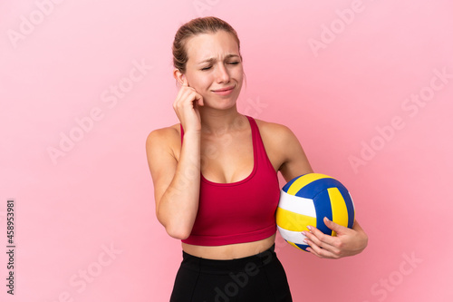 Young caucasian woman playing volleyball isolated on pink background frustrated and covering ears