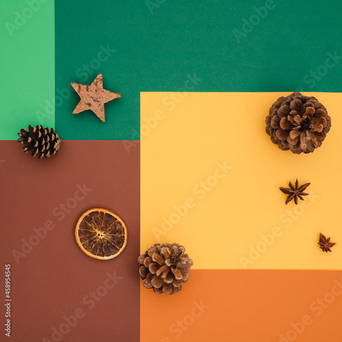 Colorful fall pattern made of autumn vibrant colors, green, brown, yellow and orange, decorated with pine cones, anis, wooden star and oranges. Creative flat lay idea perfect for October background.