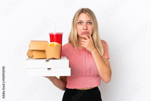 Young caucasian woman holding fat food isolated on blue background thinking