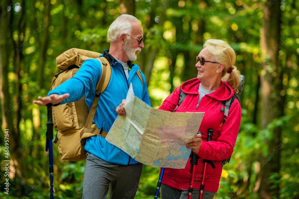 Happy senior couple of tourists looking at map in forest Happy senior couple of tourists looking at map in forest