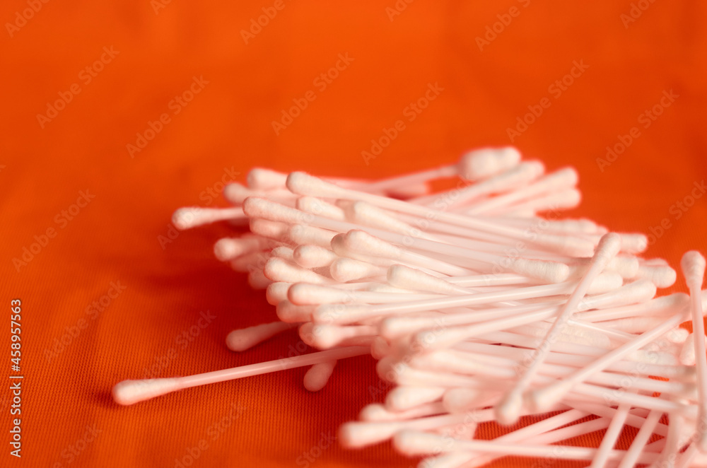 Scattered cotton swabs for the ears on an orange background Scattered cotton swabs for the ears on an orange background