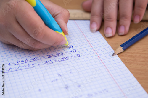 Close-up pupil's hand solves a geometric problem in a notebook. A schoolboy performs a task at the workplace. The concept of children's education, teaching knowledge, skills and abilities.