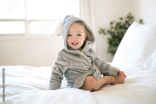 portrait of beautiful child wearing bathrobe lying on bed and smile after shower