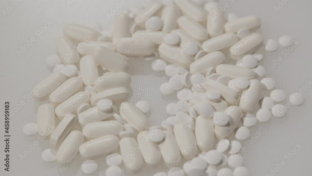 Hand grabbing pill from pile of various pills
