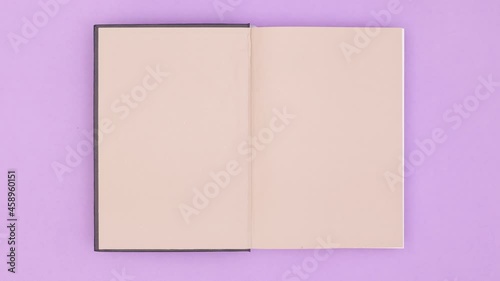Wallpaper Mural Black old vintage hardcover book appear on purple background and open. Stop motion Torontodigital.ca