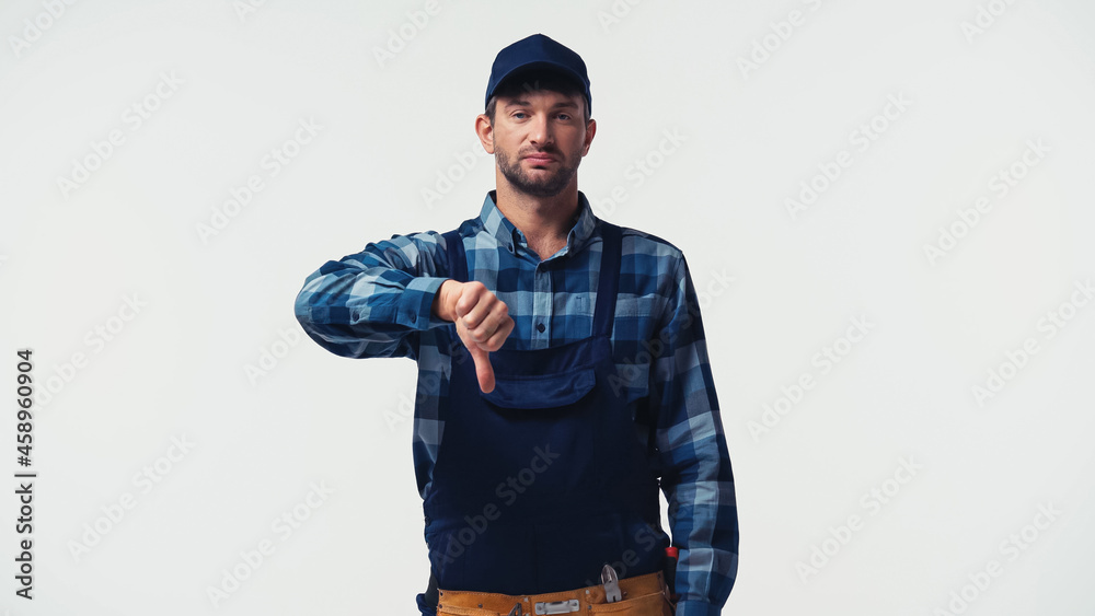 Repairman in overalls showing dislike sign isolated on white Repairman in overalls showing dislike sign isolated on white