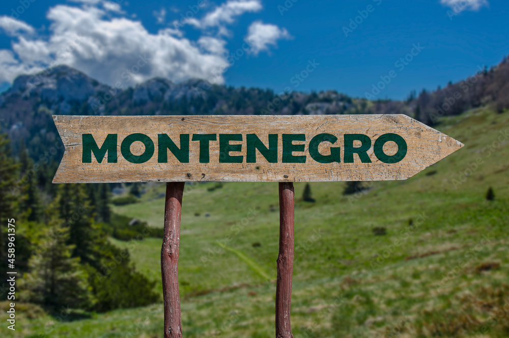 Montenegro wooden arrow road sign against mountain valley background. Travel to Montenegro concept.