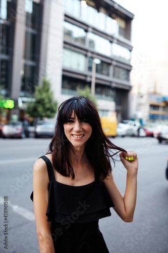 Portrait of young brunette smiling woman looking at camera. Happy girl on the street in downtown.  Selective focus  art grain