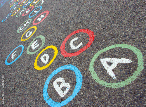 Letters of the alphabet in colored circles on an asphalt road