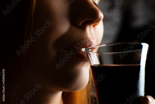 Middle aged woman drinking wine from glass in the dark