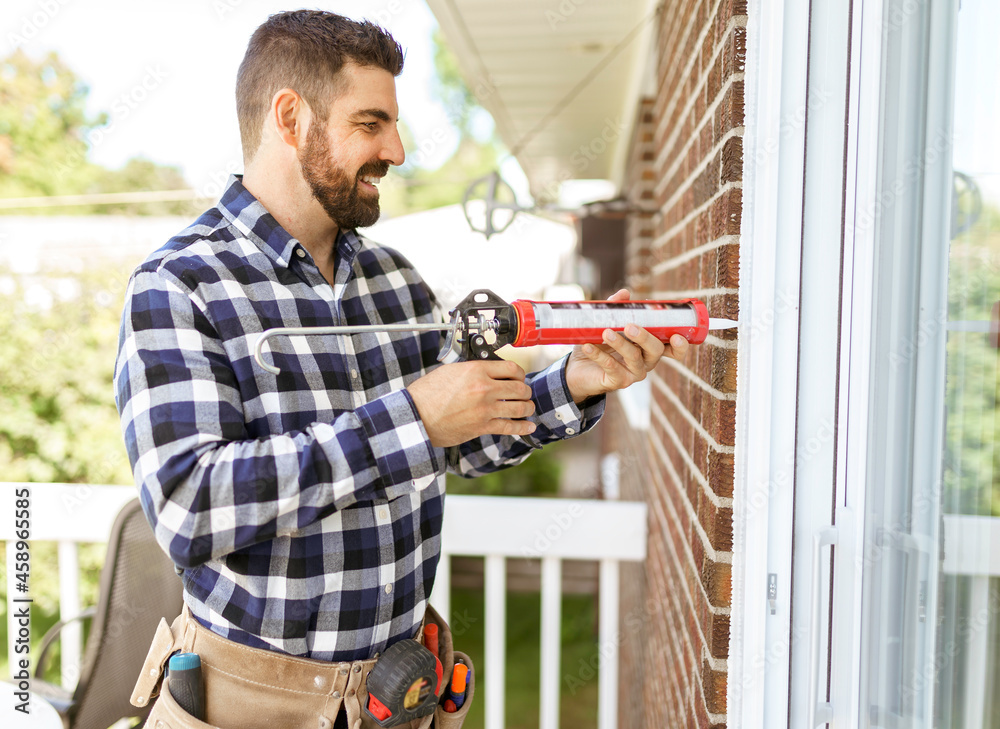 handsome young man installing bay window in a new house construction site