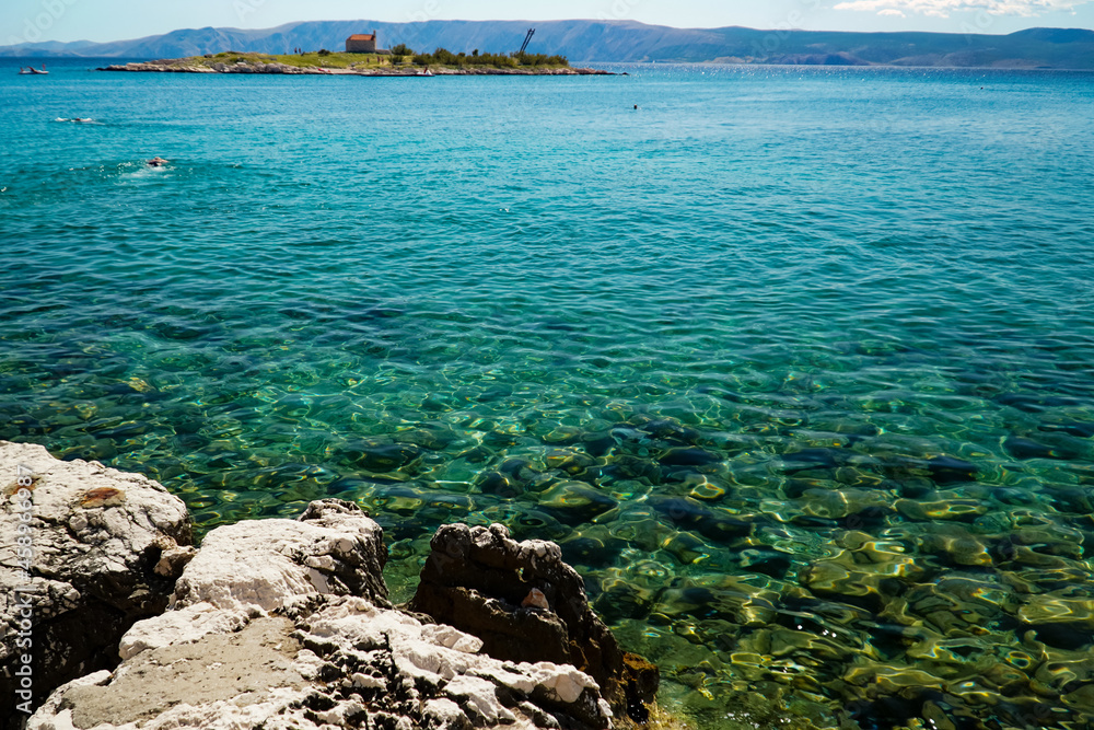 clear sea water, stones growing out of the water on the background of the island , the sea surface, the Adriatic Sea 