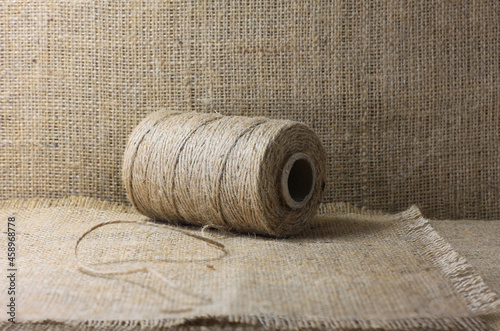 Spool of brown thread for burlap on brown burlap background with beautiful brown fabric canvas texture as vintage burlap background with burlap texture