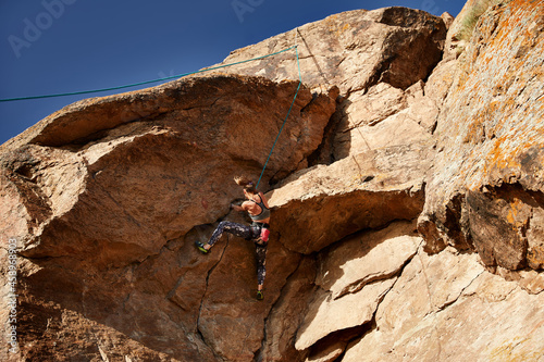 Young woman climbing at the high rock