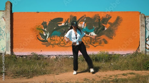 Girl dancing shuffle at the orange wall in the Charleston style