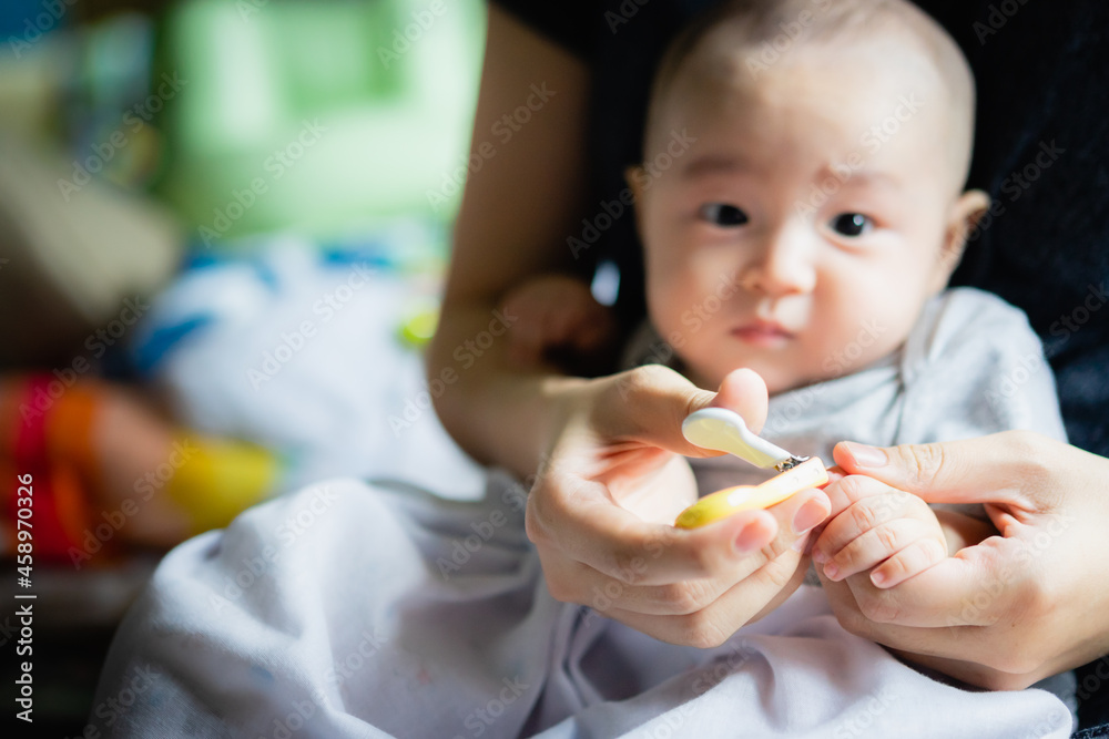 Asian Baby getting finger nails cut by his mother with scissors the concept of motherhood and care. Asian Baby getting finger nails cut by his mother with scissors the concept of motherhood and care.