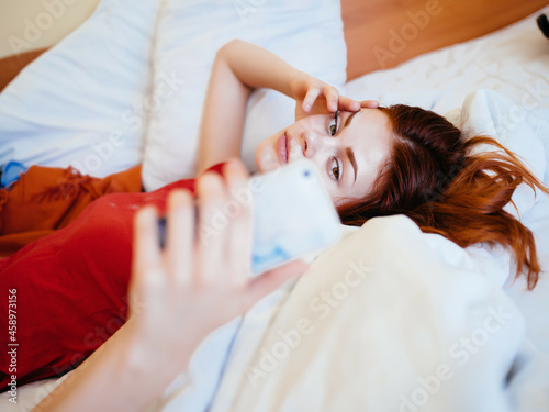 a woman lies on a bed with a phone in her hands rest Comfort of communication