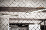 Chain-link fence in the warehouse. Wire fence in pale colors